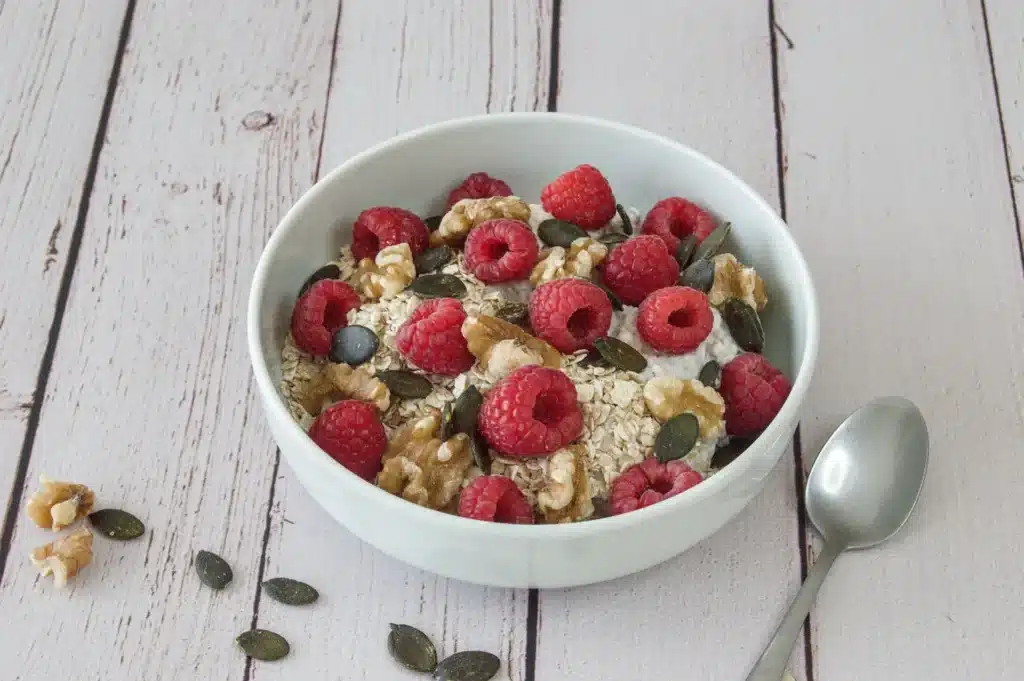 Bol de skyr avec flocons d'avoine, framboises fraîches, noix et graines de courge.