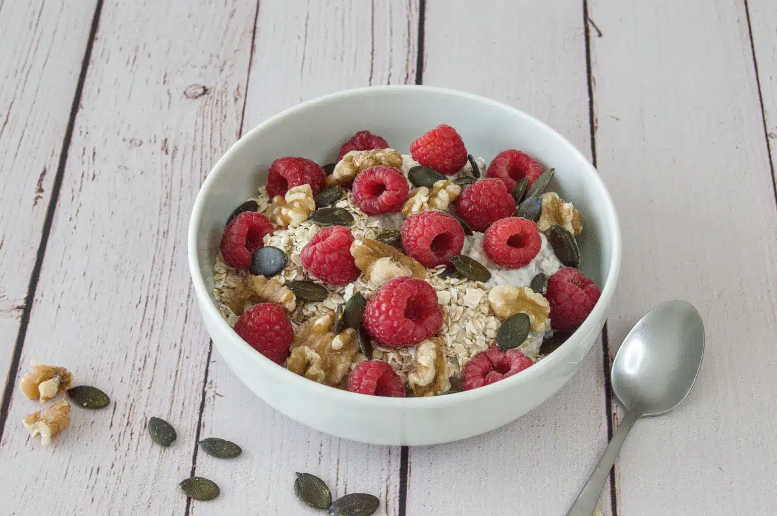Bol de skyr avec flocons d'avoine, framboises fraîches, noix et graines de courge.