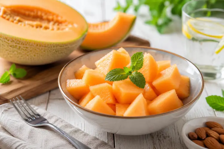 Peut-on manger du melon quand on est diabétique ? Bol de morceaux de melon frais accompagné d'amandes, une collation équilibrée adaptée aux personnes vivant avec un diabète.